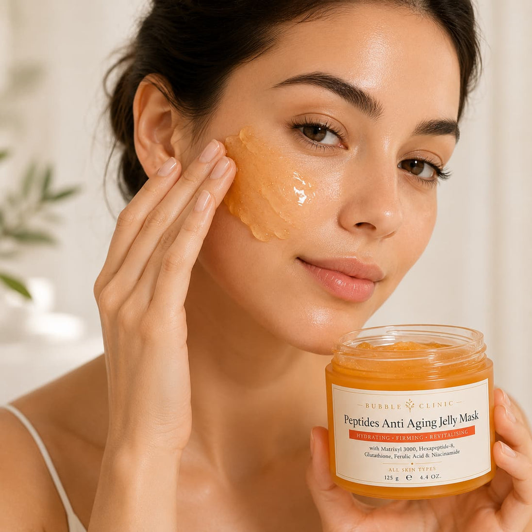 Woman applies Premium Bubble Clinic Peptides Anti Aging Jelly Mask with luxury skincare packaging, overnight hydrating jelly face mask enriched with Matrixyl 3000, Acetyl Hexapeptide-8, Glutathione, Ferulic Acid, Niacinamide and Hyaluronic Acid to improve skin hydration, firmness, elasticity and radiance while helping soften the appearance of fine lines and wrinkles.