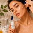 Plumping Hyaluronic Acid Serum being applied by woman to her cheek. The bottle label reads 'Bubble Clinic, Plumping Hyaluronic Acid Serum - representing best natural Australian Skincare.