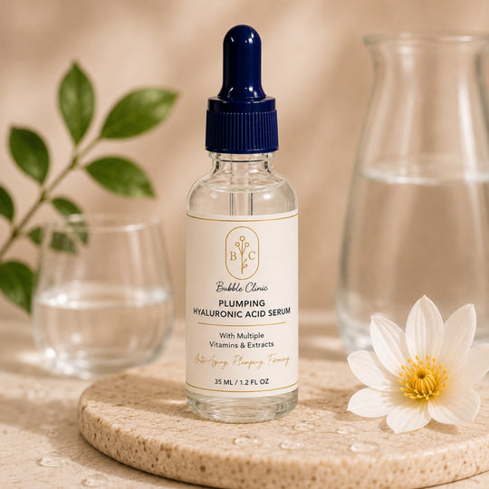 A bottle of Bubble Classic Plumping Hyaluronic Acid Serum with a dark blue dropper cap and cream label, styled on a stone coaster with a white flower and glassware in a warm beige setting.
