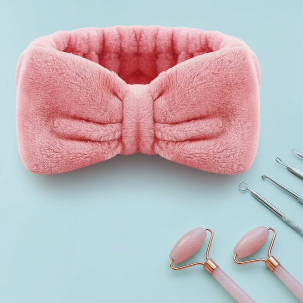 close up of original, adult size spa headband in pink against pink background with skincare essentials. 