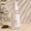 Close-up of Radiance Peptide Serum frosted bottle and white dropper on beige and stone backdrop