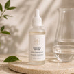 Bubble Clinic Radiance Peptide Serum in a filled 50 mL frosted dropper bottle on a beige background and stone surface.