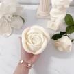 rose soy wax candle held against luxurious backdrop with botanicals and decorative candles on a marble benchtop representing Australian made natural home fragrance.