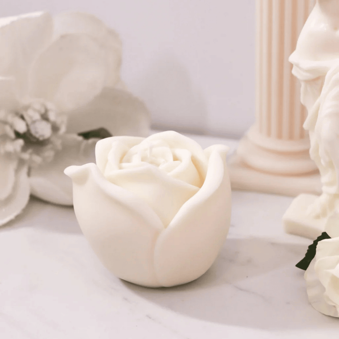 rose soy wax candle with botanicals and decorative candles on a marble benchtop representing Australian made natural home fragrance.