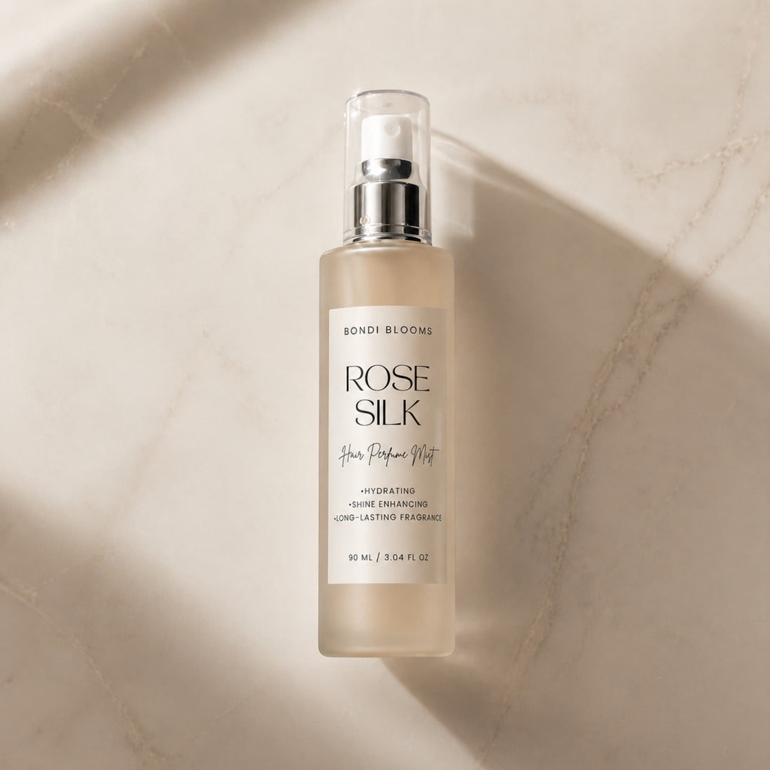 Bottle of rose silk hair perfume mist on a beige marble surface representing best hair perfume australia.