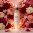 Bottle of Bondi Blooms Rose Silk hair perfume mist surrounded by roses and heart decorations.