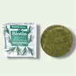 Biotin & Rosemary Shampoo Bar. Infused with spirulina, amla oil, and refreshing peppermint for scalp health and shine on a lime background with package box. Sulfate-free and natural.