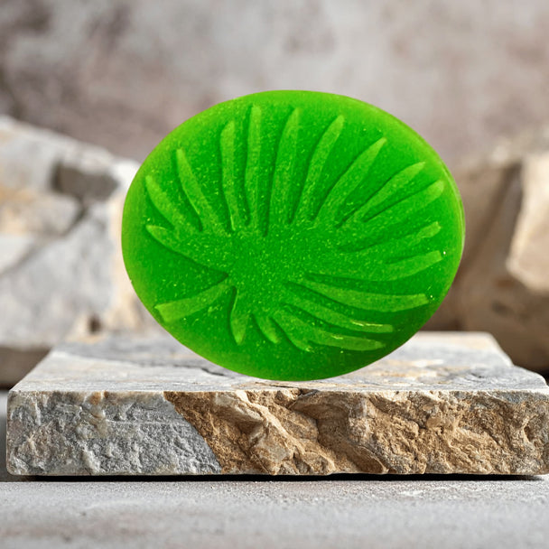 Green leaf-shaped soap free solid face wash with sulphur and salicylic acid on a stone surface with a blurred natural background