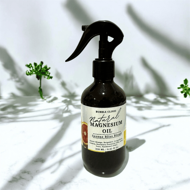 Bottle of natural magnesium oil infused with essential oils with a label on a marble surface with plant shadows.