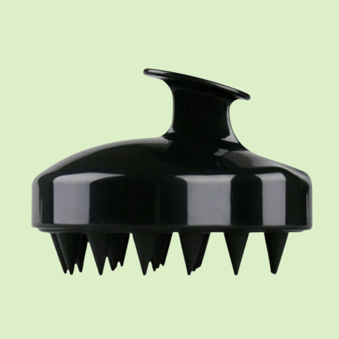 close up of soft silicone scalp brush - black with splash of water against white background. soft bristles stimulate hair growth and remove dandruff, awaken hair follicles.