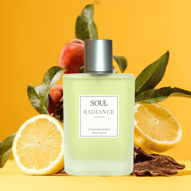 Perfume bottle labeled 'Soul Radiance' surrounded by fruits, flowers, and spices representing the natural essential oils and floral fruity citrus notes in the perfume on a yellow background