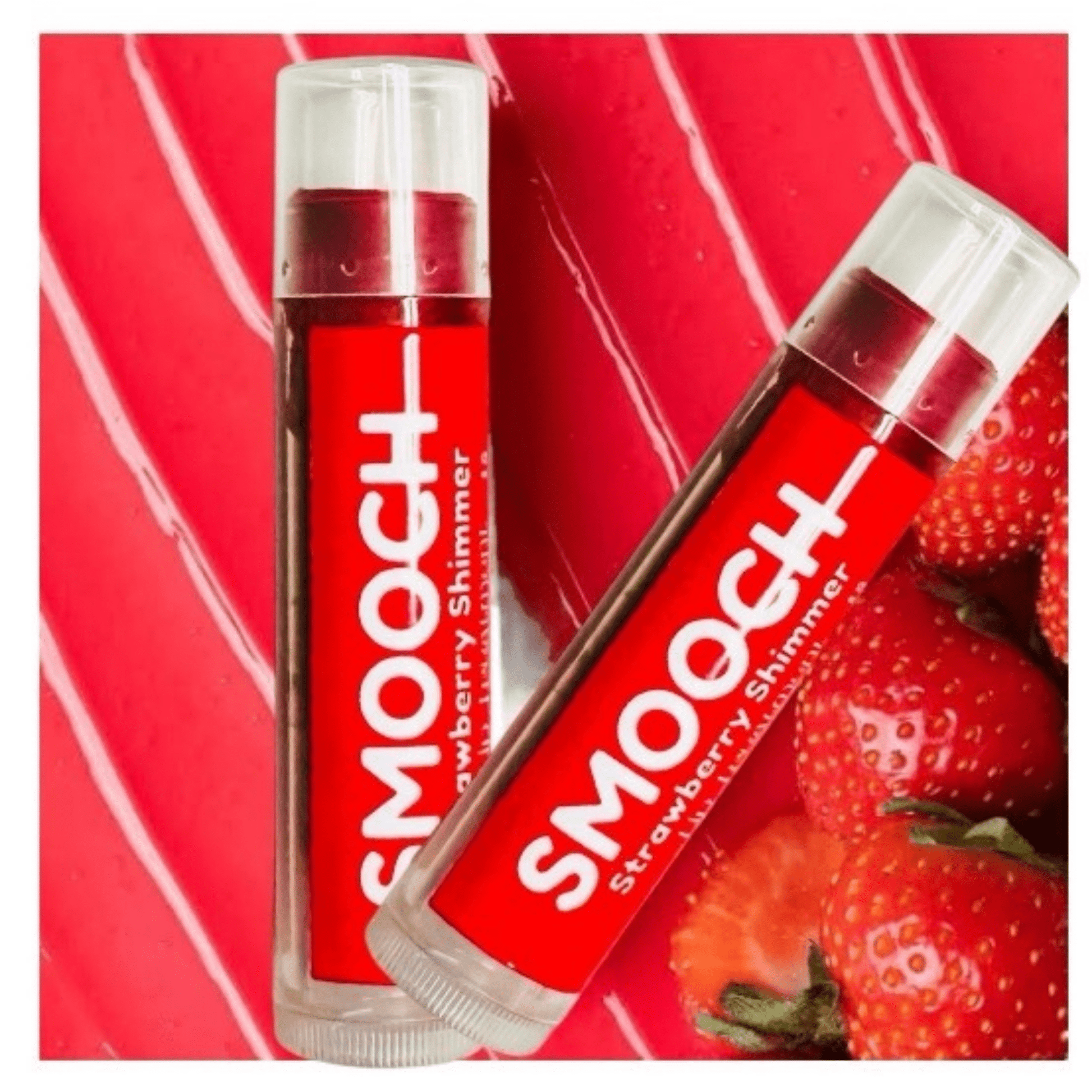 Two red strawberry tinted lip balm on red background with fresh strawberries highlighting natural, organic ingredients.