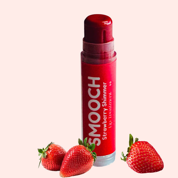 Strawberry lip balm on clean white background with fresh strawberries representing clean natural lip care.