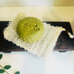 close up of one comfrey sulphur bar for acne, rosacea and troubled skin against clean light background with organic botanicals in foreground representing best natural acne and troubled skin treatments for sensitive skin.