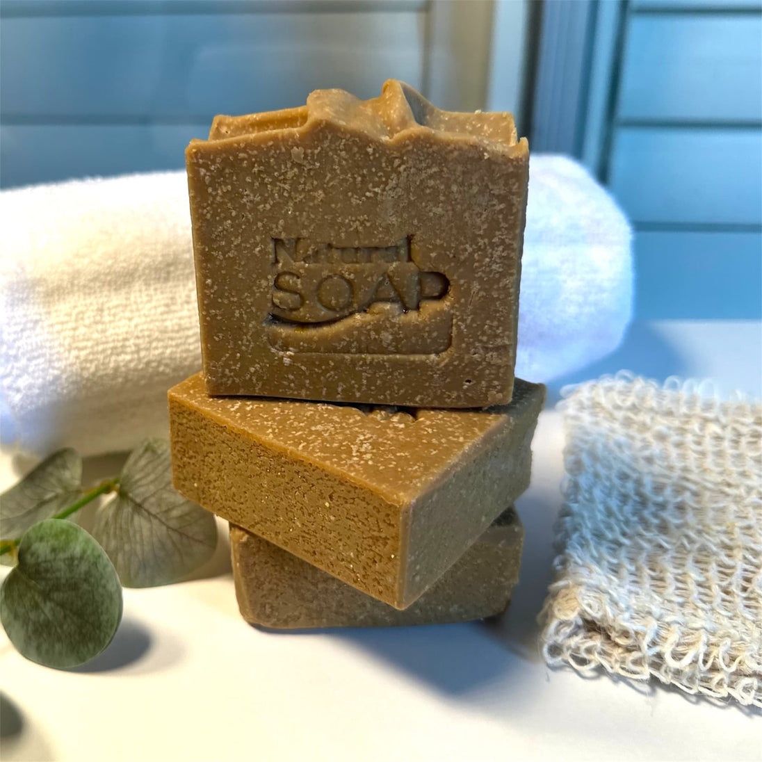 close up of 3 bars of sulphur soap with emu oil and msm stamped natural soap with botanicals in the foreground and towel in background representing natural Australian skincare.