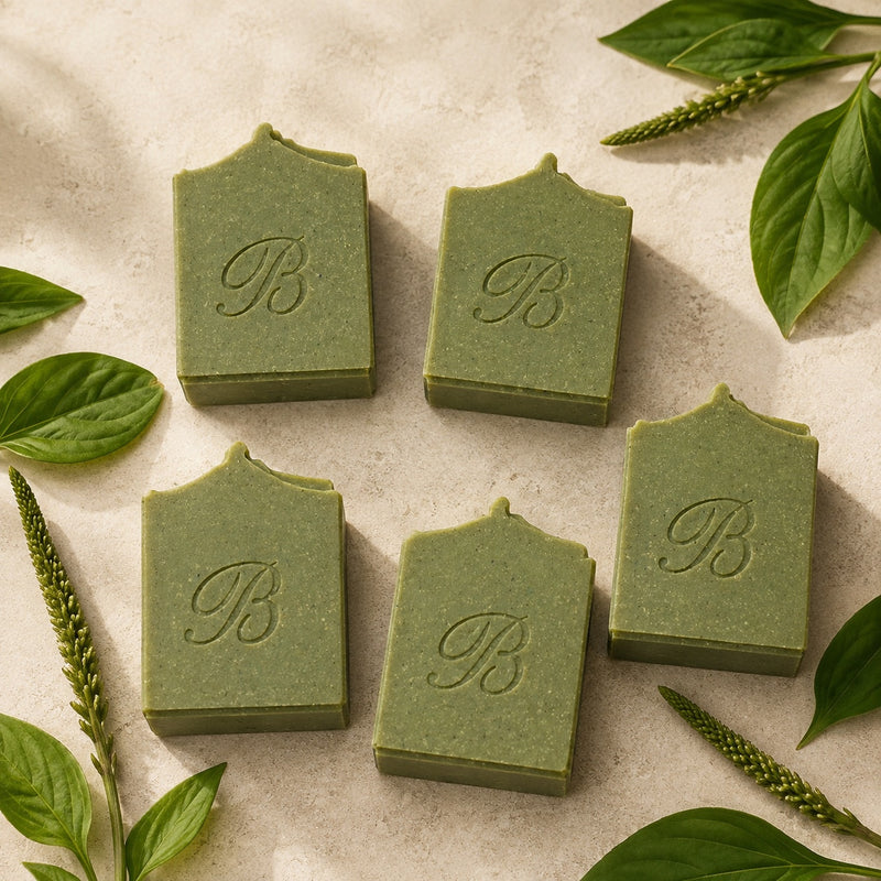 Four handmade sulphur soap bars with plantain and comfrey on a warm ivory background with botanical leaves.