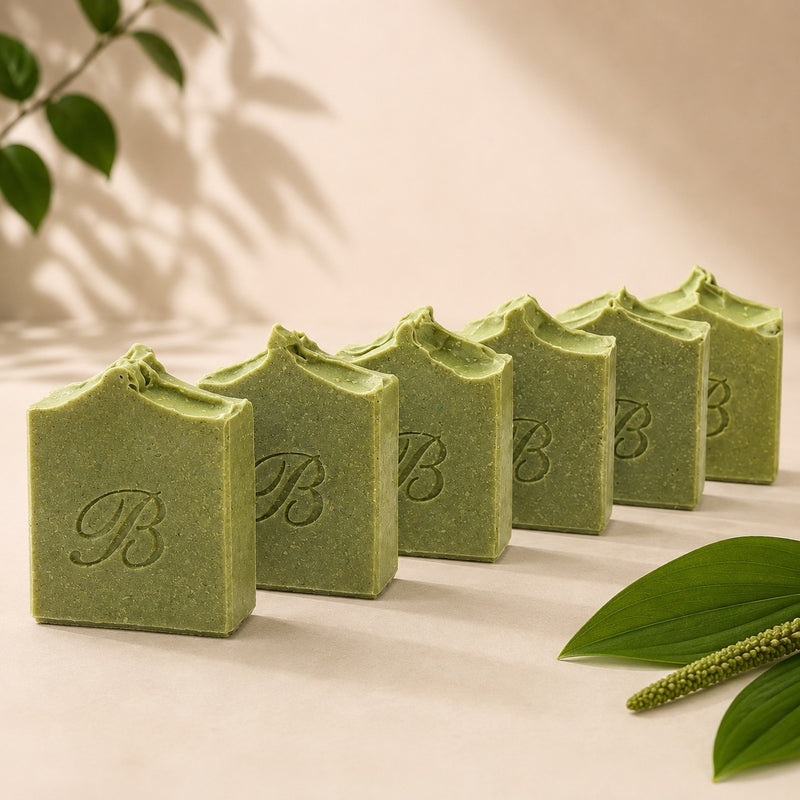 Lineup of handmade green sulphur soap bars with plantain and comfrey, showing sculpted tops and stamped fronts.
