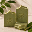 Three-view arrangement of handmade sulphur soap with plantain and comfrey, showing front, top and side texture.