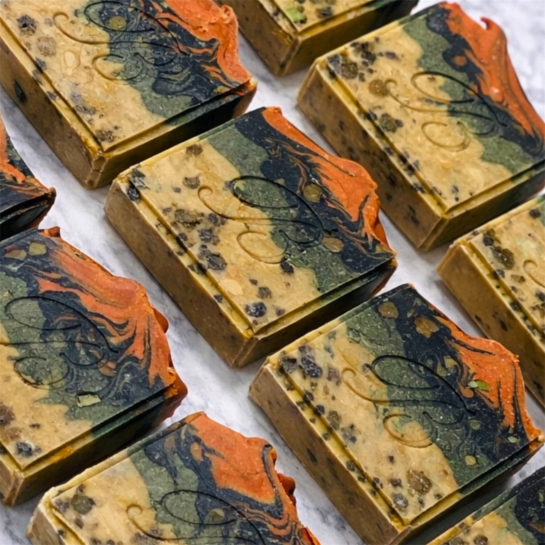 Marbled sulphur soap bars in orange, green, and beige for blemishes and troubled skin with a brand logo on a marble surface representing natural Australian skincare for blemishes and troubled skin on a white background