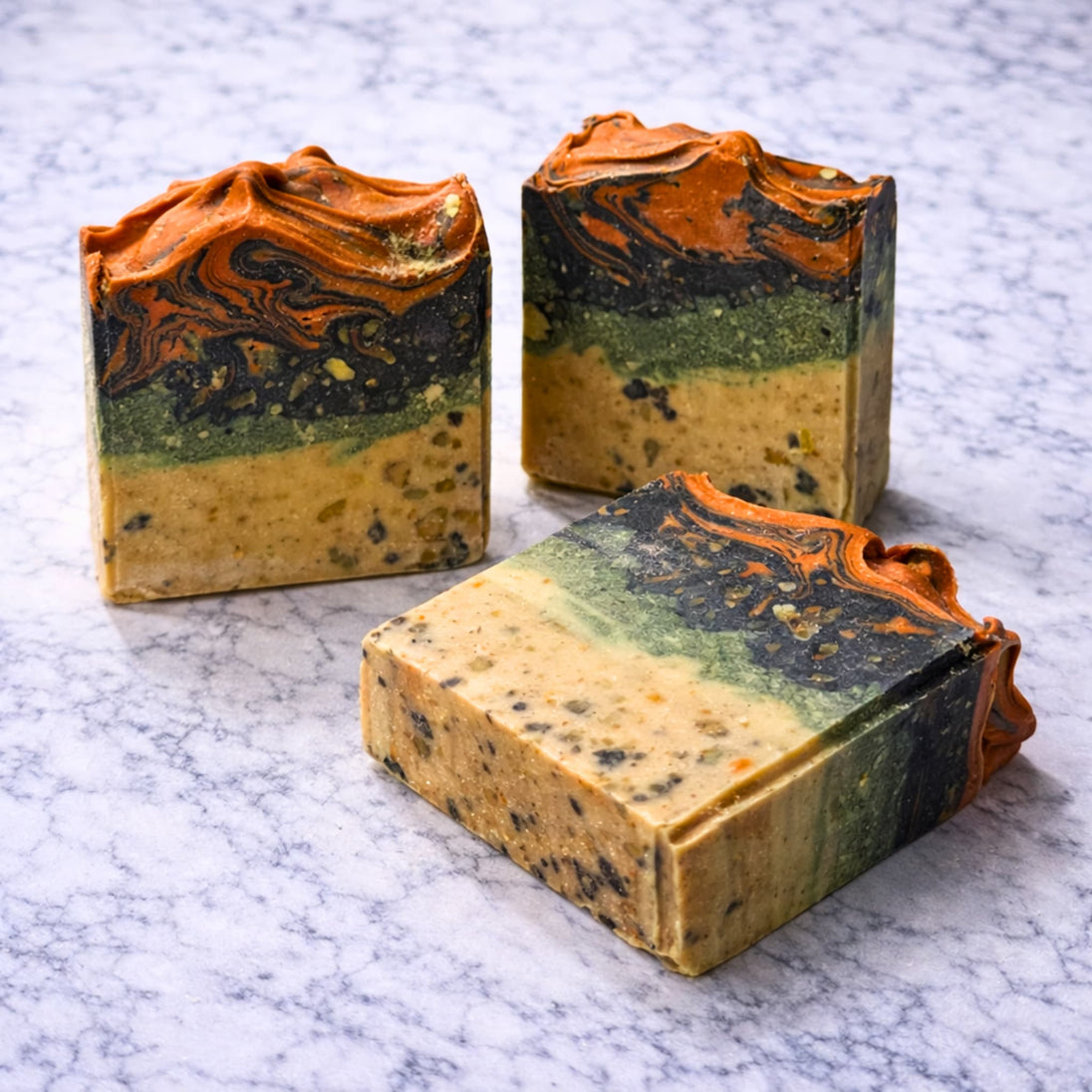 Three marbled sulphur soap bars in orange, green, and beige for blemishes and troubled skin with a brand logo on a marble surface representing natural Australian skincare for blemishes and troubled skin on a white background
