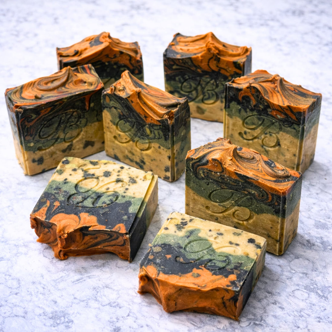 Marbled sulphur soap bars in orange, green, and beige for blemishes and troubled skin with a brand logo on a marble surface representing natural Australian skincare for blemishes and troubled skin on a white background