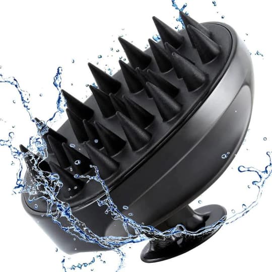 close up of black silicone scalp massage brush with soft bristles against white background and splash of water representing natural australian haircare essentials.