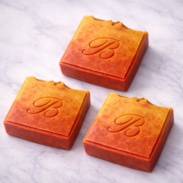 Close up of 3 flat laid natural pink and yellow turmeric, alpha arbutin soap with kojic acid and himalayan rhubarb scented in a beautinful natural rose fragrance and packed with organic turmeric, turmeric tallow and oils for brighter and even skin tone. 