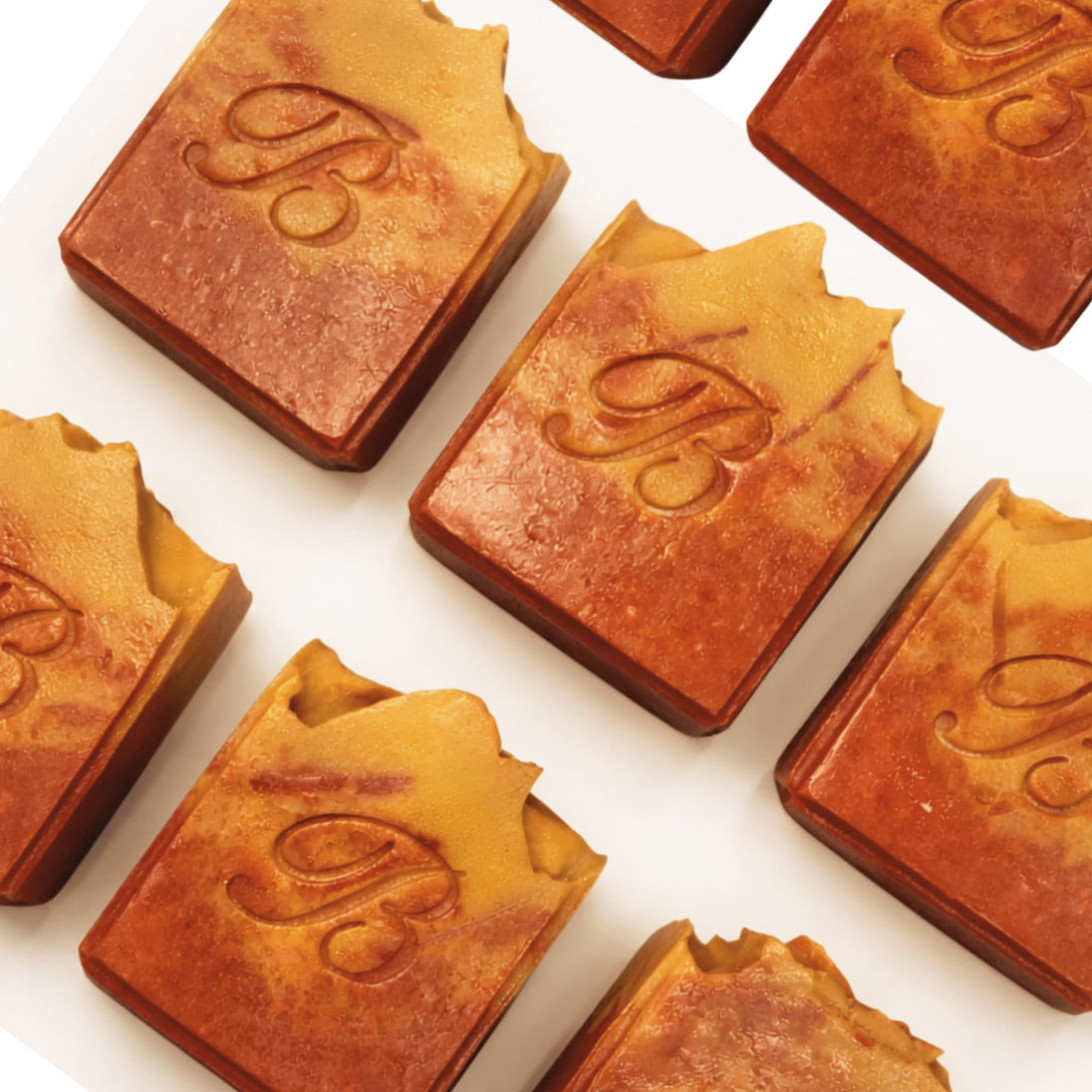 Close up of flat laid natural pink and yellow turmeric, alpha arbutin soap with kojic acid and himalayan rhubarb scented in a beautinful natural rose fragrance and packed with organic turmeric, turmeric tallow and oils for brighter and even skin tone. 