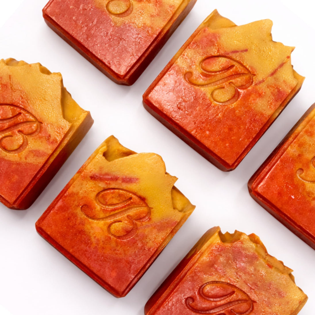 Close up of 6 flat laid natural pink and yellow turmeric, alpha arbutin soap with kojic acid and himalayan rhubarb scented in a beautinful natural rose fragrance and packed with organic turmeric, turmeric tallow and oils for brighter and even skin tone. 