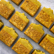 Close up of flat laid turmeric alpha arbutin soap with kojic acid, turmeric tallow and oil and scented with essential oil on a light marble surface representing best brightening organic soap Australian made.