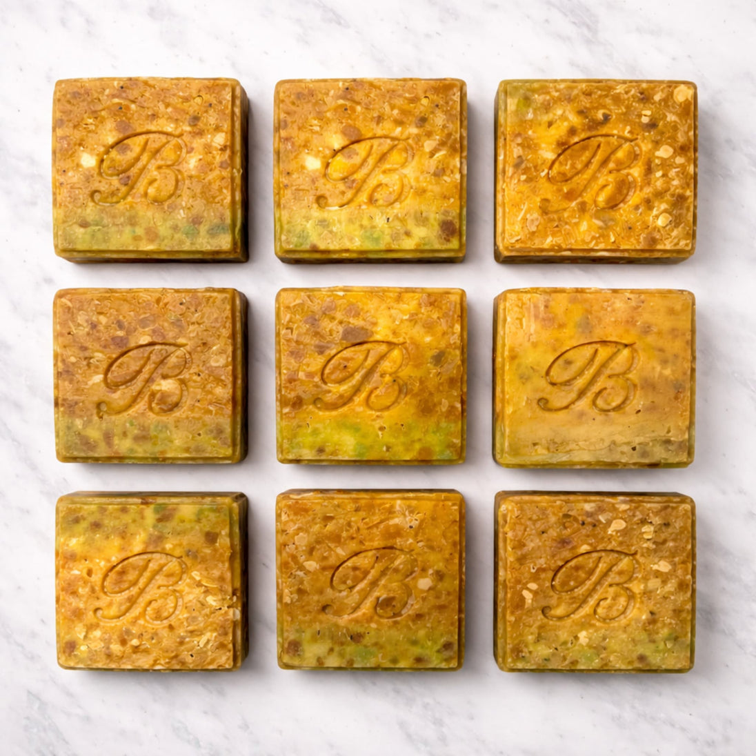Close up of square turmeric alpha arbutin soap with kojic acid, turmeric tallow and oil and scented with essential oil on a light marble surface representing best brightening organic soap Australian made.