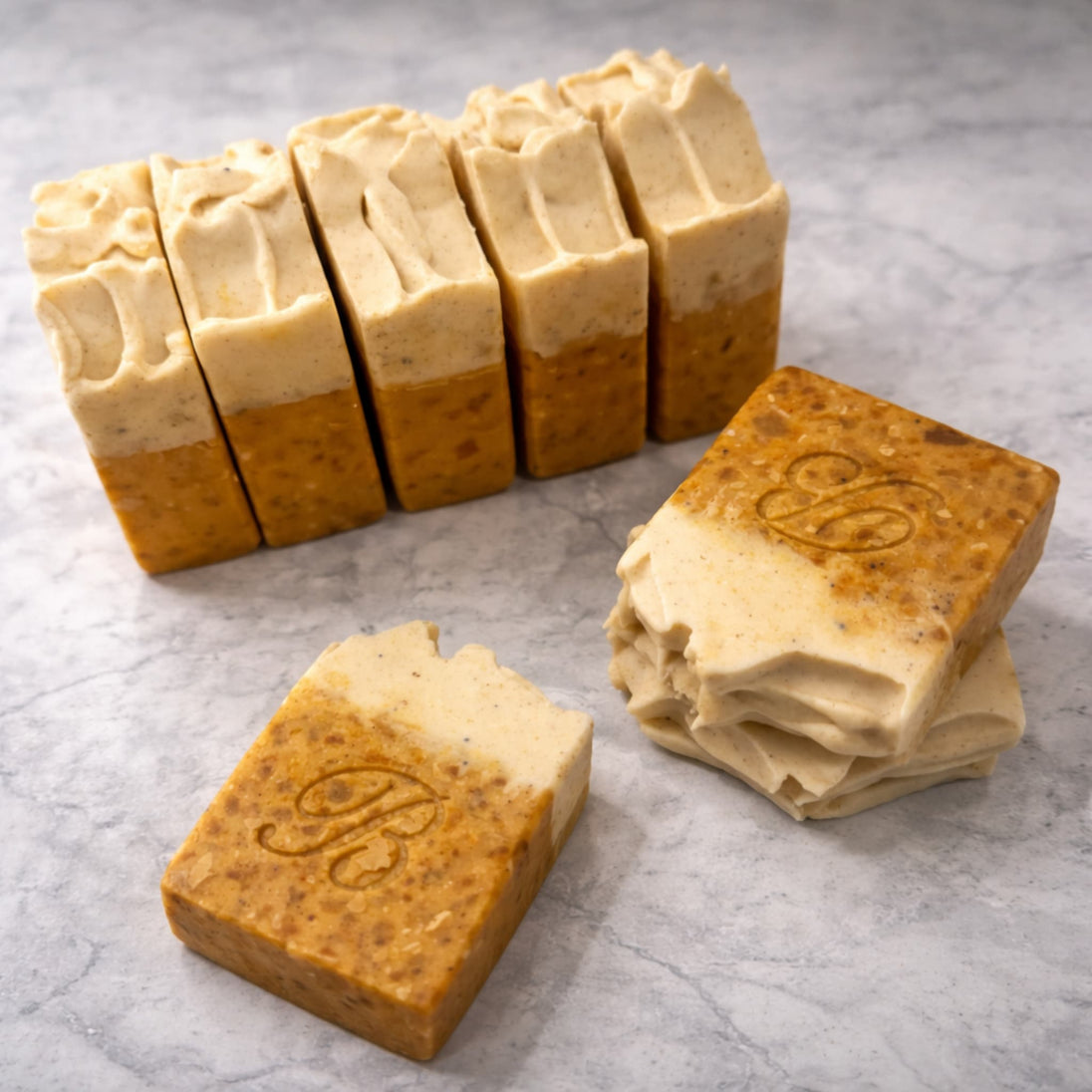 Close up of textured turmeric alpha arbutin soap with white top made with kojic acid, turmeric tallow and oil and scented with peppermint essential oil on a light marble surface representing best brightening organic soap Australian made.