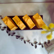 close up top view of 4 organic brightening, bright yellow, kojic turmeric soap bars with botanicals in the foreground. 