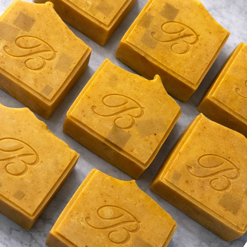 Bright yellow turmeric and kojic acid artisan soap bars on a neutral background