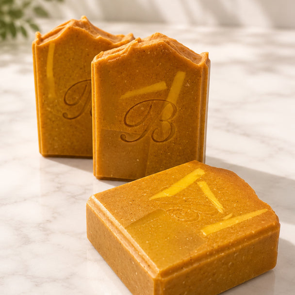 Three rectangular bars of textured turmeric and kojic acid soap standing on a light marble surface, representing best brightening turmeric soap Australian.