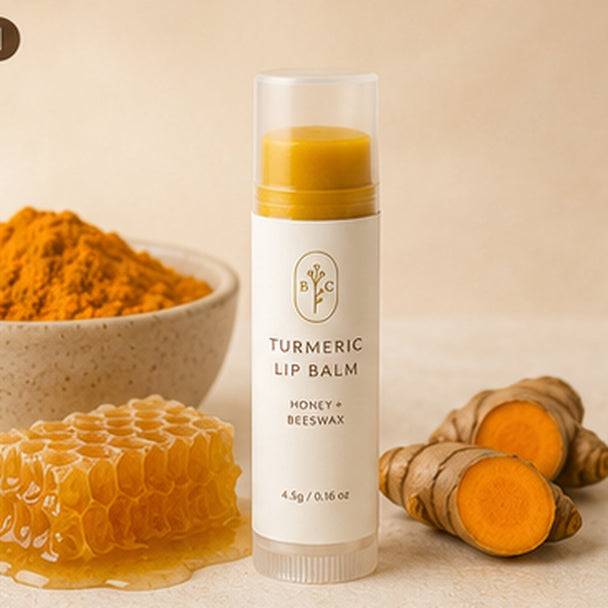 Turmeric lip balm with honey and beeswax in premium cream packaging beside turmeric root and honeycomb