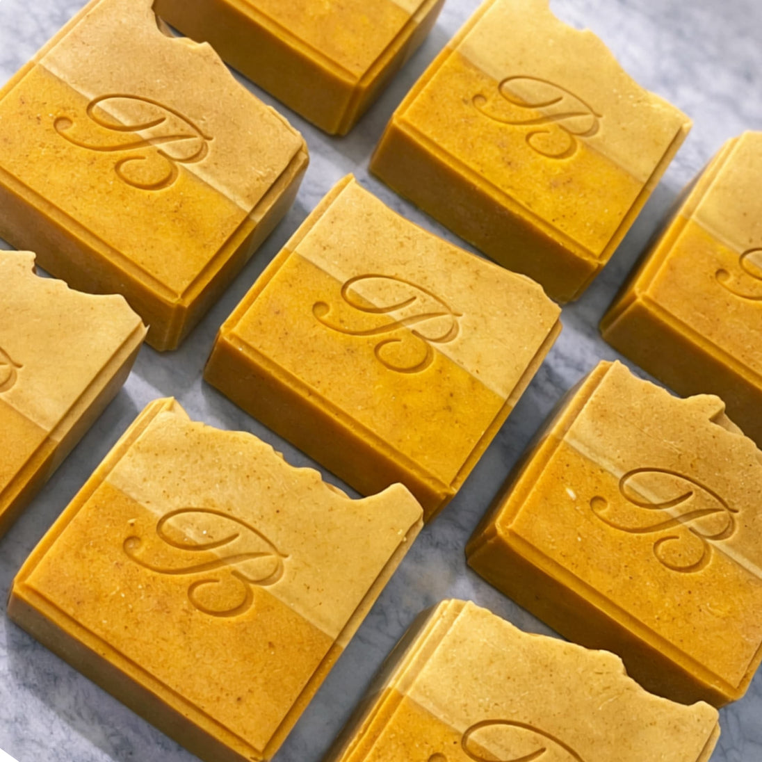 close up of turmeric Vitamin C soap with kojic acid and natural oils and butters flat laid on a marble surface representing best brightening soap with turmeric, vitamin c and kojic acid. 