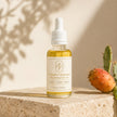 Bubble Clinic Vitamin C Radiance Face Oil in a filled 30 mL clear bottle with white dropper on warm travertine.