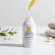 white ceramic bottle with dropper over it revealing clear yellow hue of vitamin c oil with prickly pear on a white background with botanicals and towels representing clean natural australian skincare